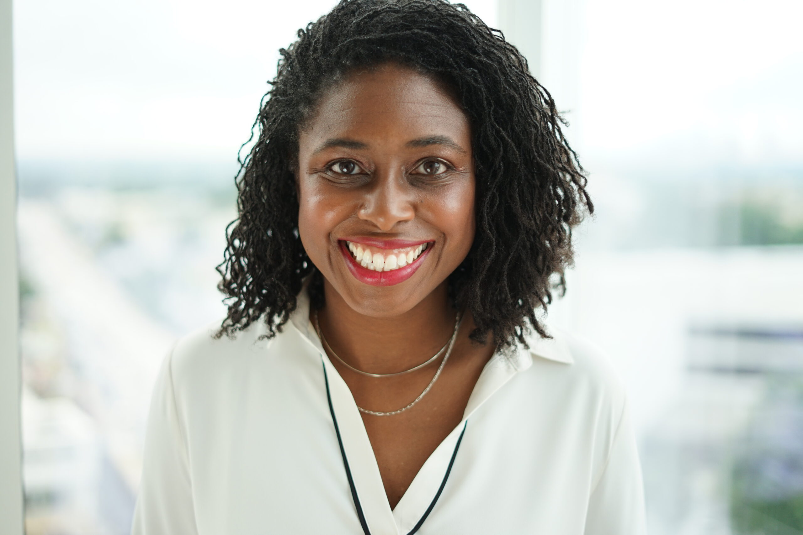 Smiling woman in white shirt indoors portrait.