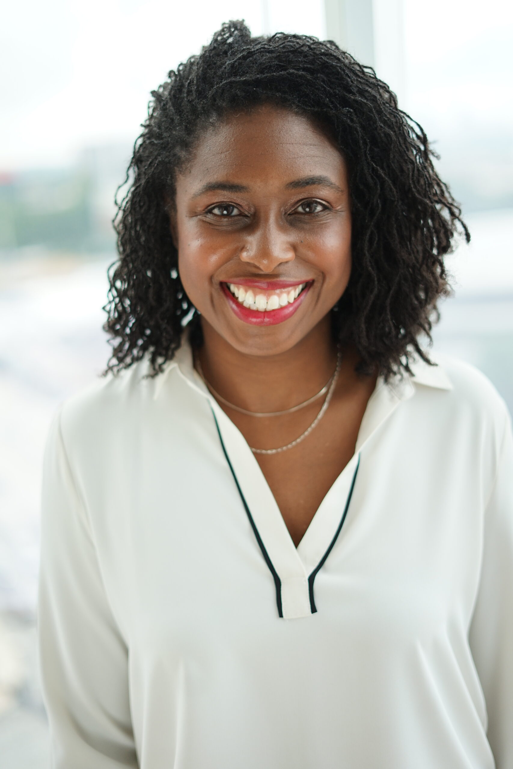 Smiling woman with curly hair and necklace